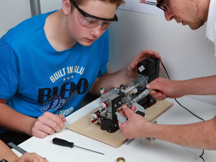 UNIMAT technic set in the classroom, teachers is measuring a workspiece together with a student